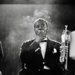 American jazz trumpeter, composer and singer Louis Armstrong smoking a cigarette on stage at University of Chicago Theater in the Round, IL, US, 1962.