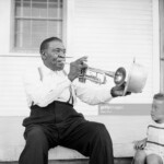 Jazz trumpeter Papa Celestine plays for his young grandson on the front porch of his house, using his hat for a mute. (Photo by © Bradley Smith/CORBIS/Corbis via Getty Images)